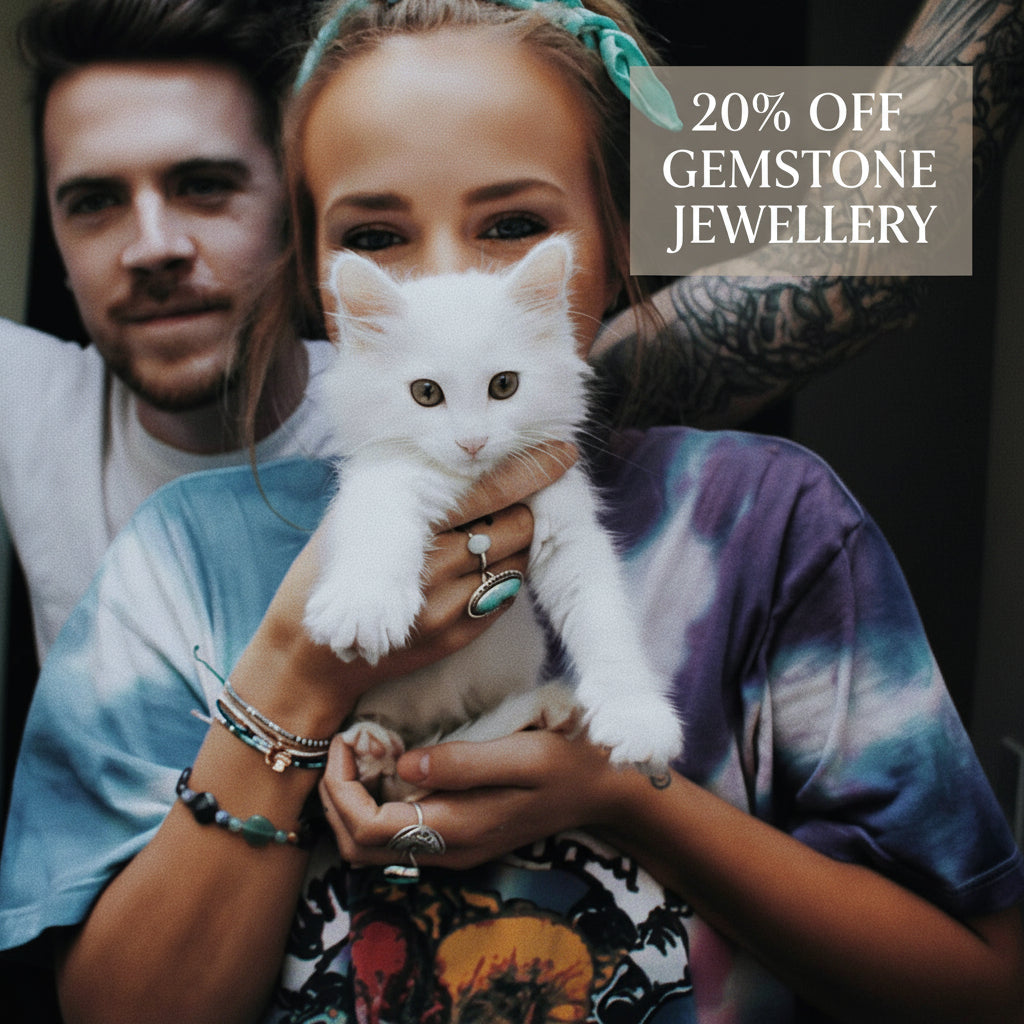 Person holding a white kitten with a person and tattooed arm in the background