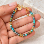 Turquoise and labradorite gold bracelet held in hand showing clasp and extender