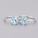 Two sterling silver blue topaz rings with oval stones on a light grey background