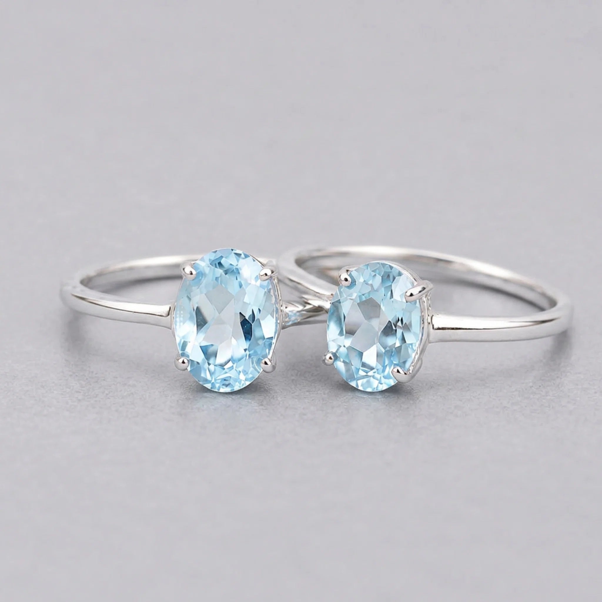 Two sterling silver blue topaz rings with oval stones on a light grey background