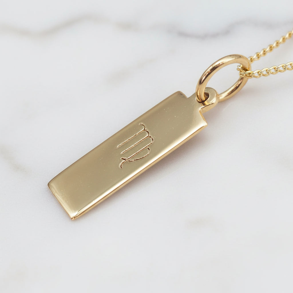 virgo zodiac necklace in gold plated sterling silver on a white stone surface