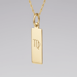 Virgo Zodiac Pendant in Gold plated Sterling Silver hanging in front of a light wall