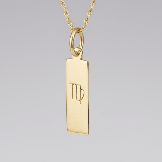 Virgo Zodiac Pendant in Gold plated Sterling Silver hanging in front of a light wall