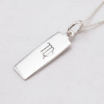 Silver necklace with a rectangular pendant featuring an engraved virgo zodiac symbol on a light gray background