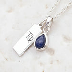 Sterling Silver necklace with a teardrop september birthstone sapphire pendant and virgo zodiac pendant on a light background