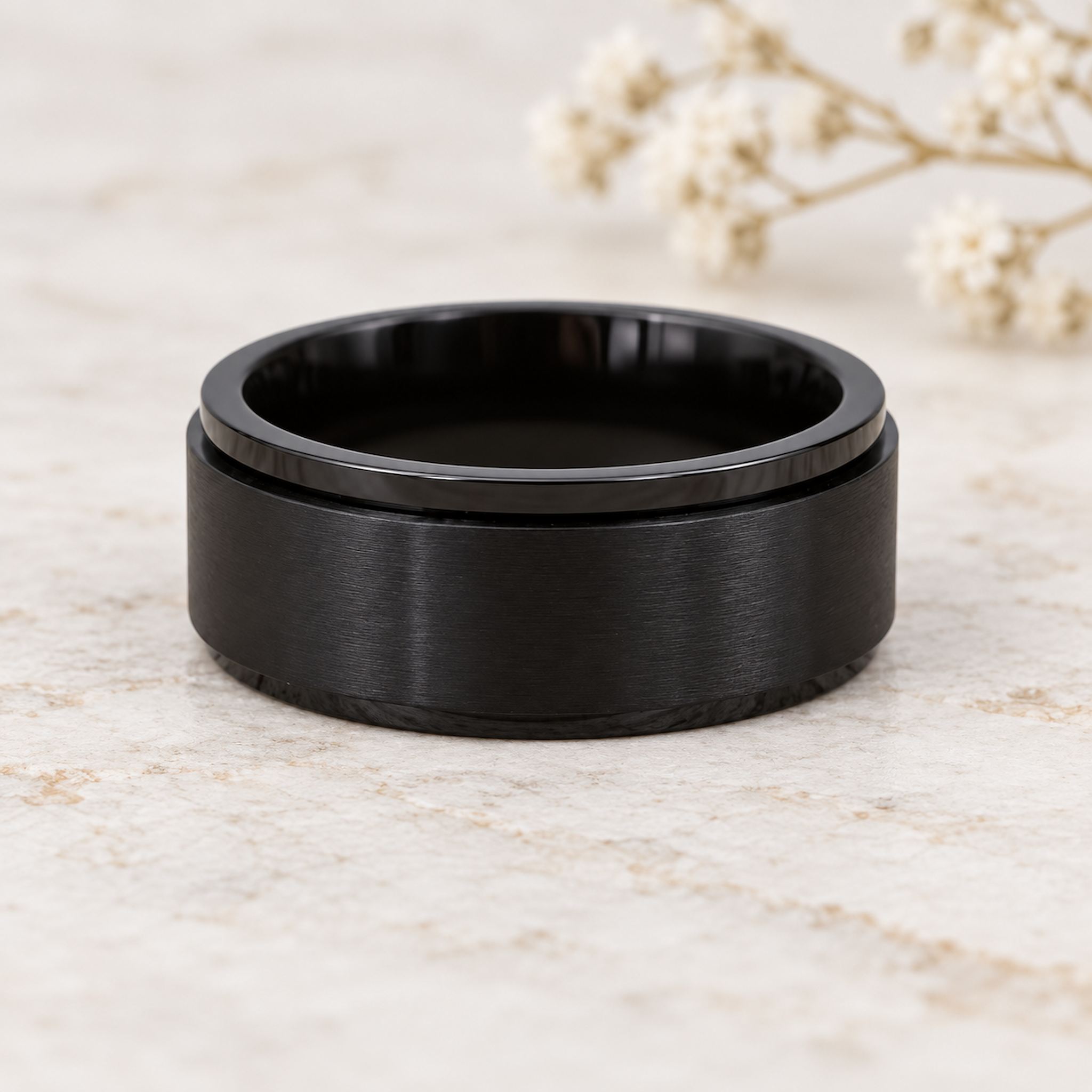 waterproof black spinner Ring in minimalist stainless steel band design on a light wooden surface