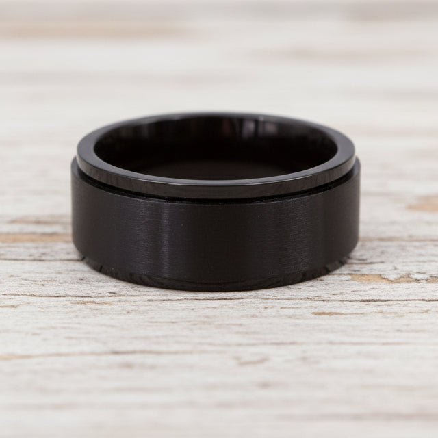 waterproof black spinner Ring in minimalist stainless steel band design on a light wooden surface