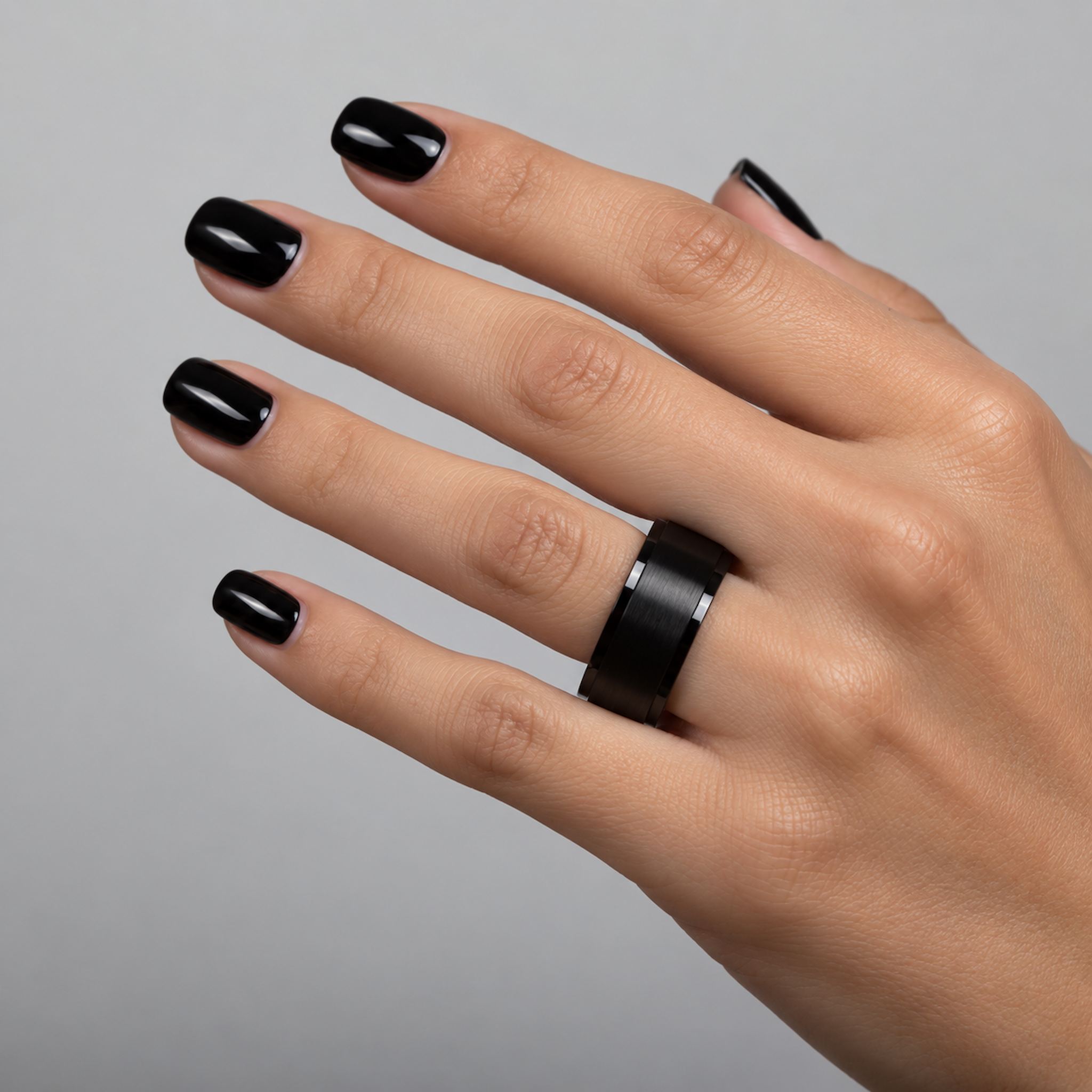 waterproof black spinner Ring in minimalist band design being worn on a womans finger with black nail polish