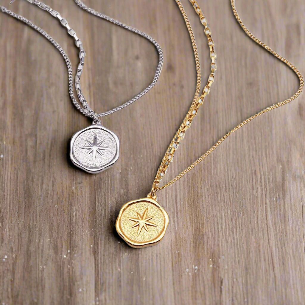two stainless waterproof necklaces in silver and gold with starburst compass pendants