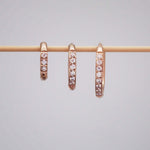 Three stainless steel waterproof pavé rose gold hoop earrings in three different hoop huggie earring sizes