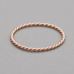 stainless steel waterproof rose gold twisted stacker ring on a grey surface