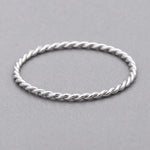 waterproof stainless steel silver twisted stacker ring on a grey surface