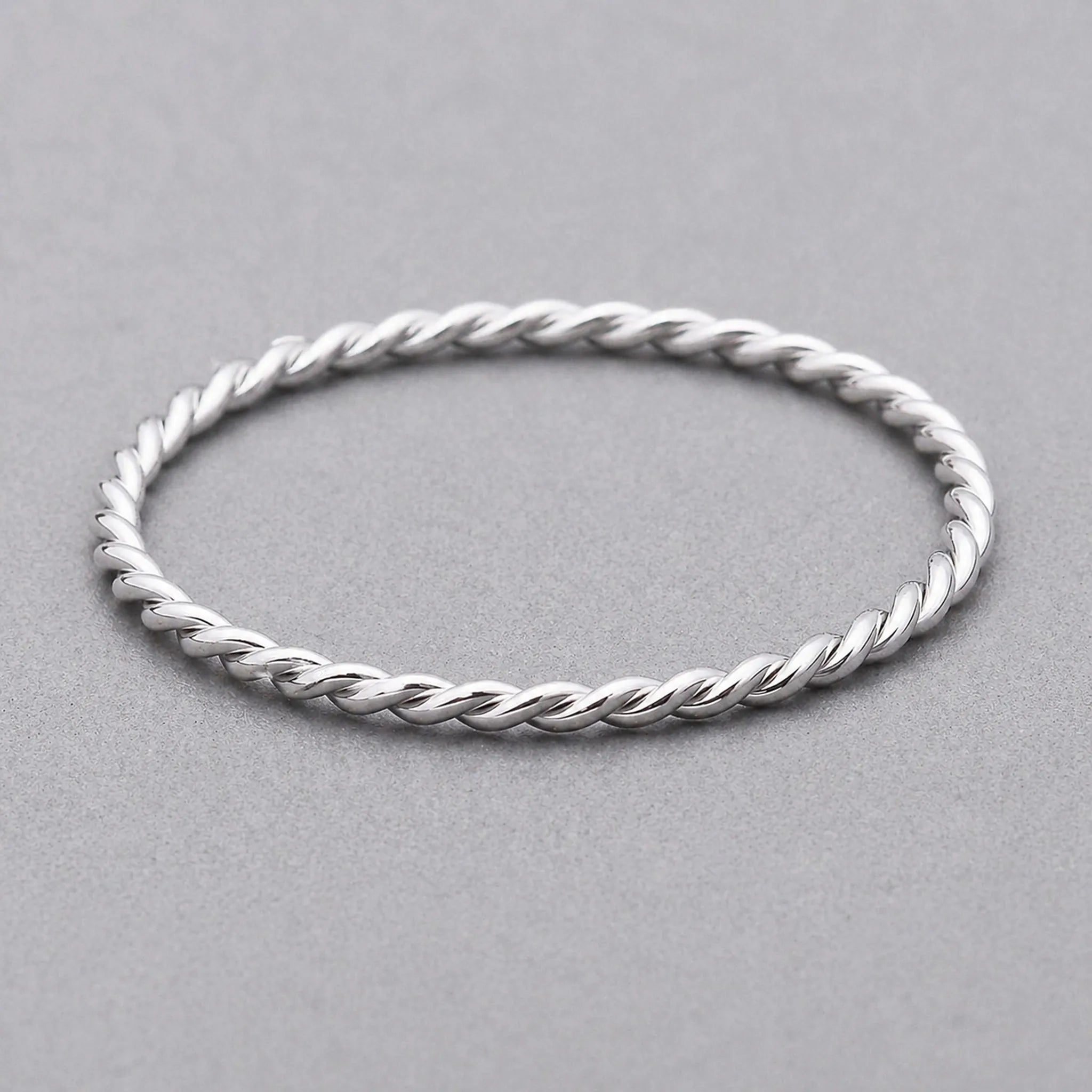 waterproof stainless steel silver twisted stacker ring on a grey surface