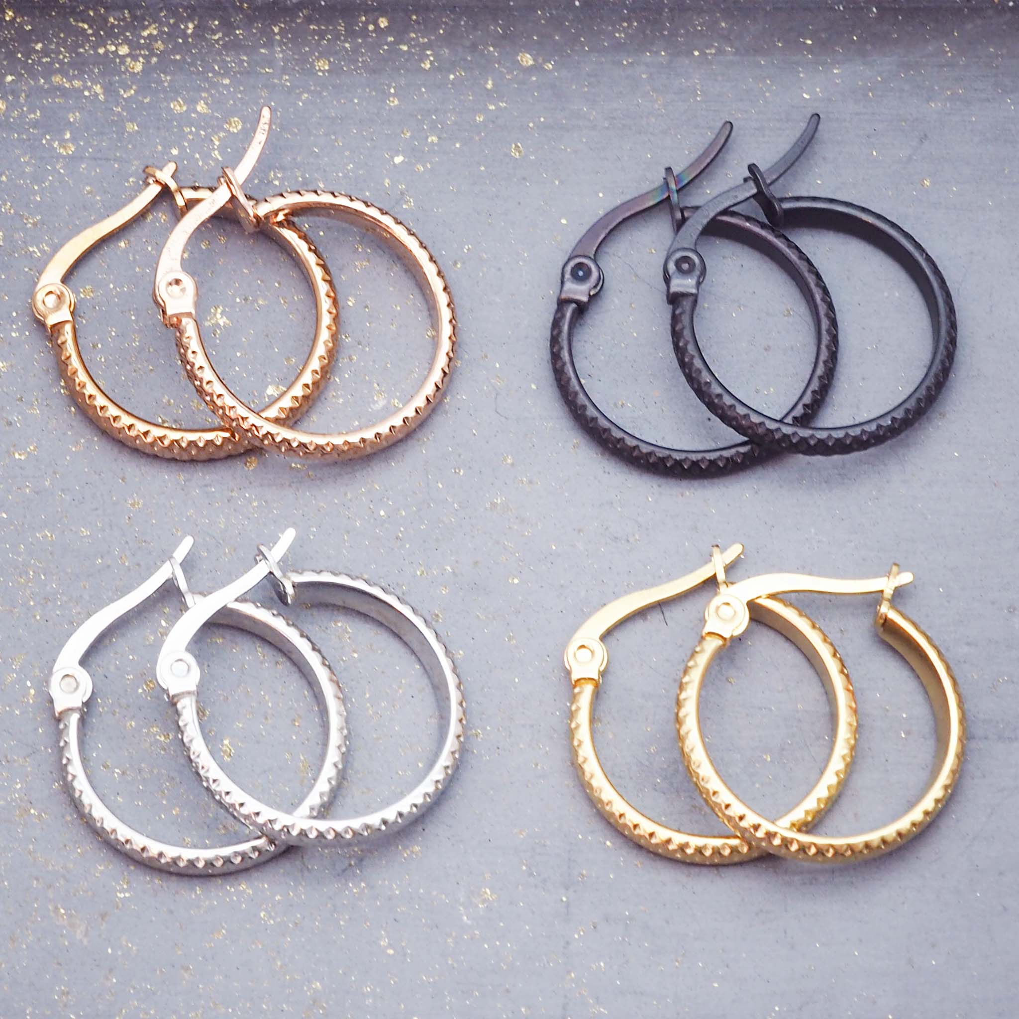 four pairs of waterproof stainless steel hoop earrings in silver, gold, rose gold and black plating with textured design