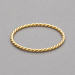 stainless steel waterproof gold twisted stacker ring on a grey surface