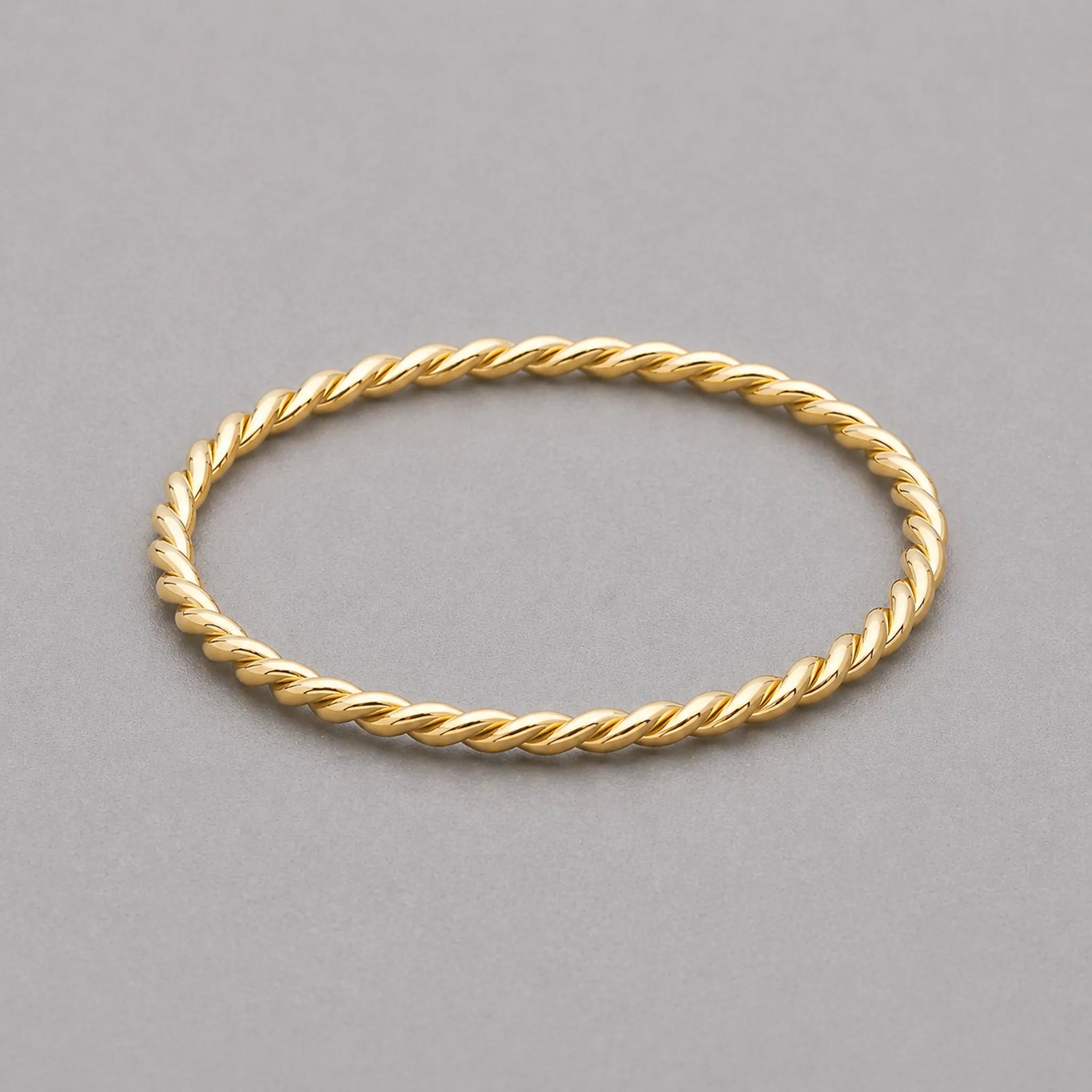 stainless steel waterproof gold twisted stacker ring on a grey surface