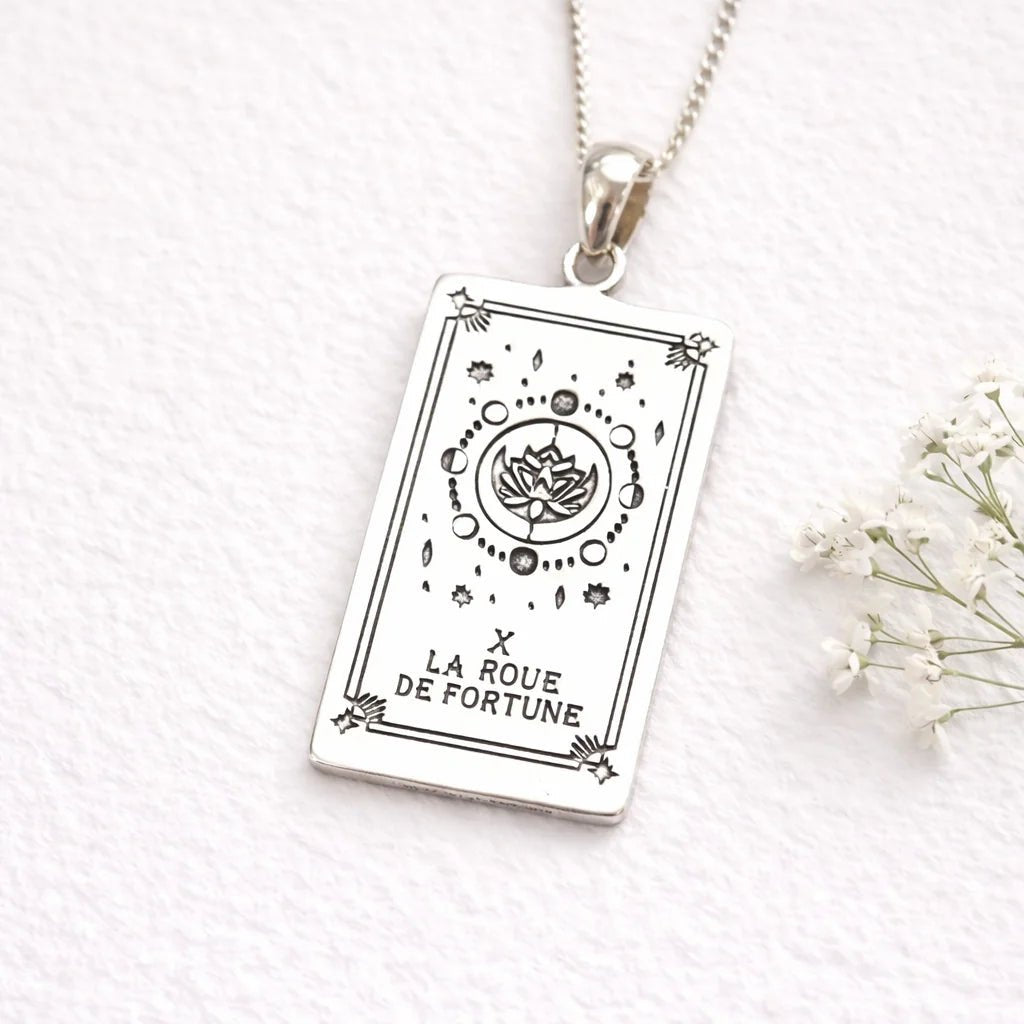 Silver pendant with Wheel of Fortune tarot card design on a white background