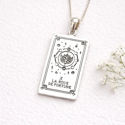 Silver pendant with Wheel of Fortune tarot card design on a white background