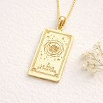 Gold Wheel of Fortune tarot card pendant necklace on a white background with dried flowers.