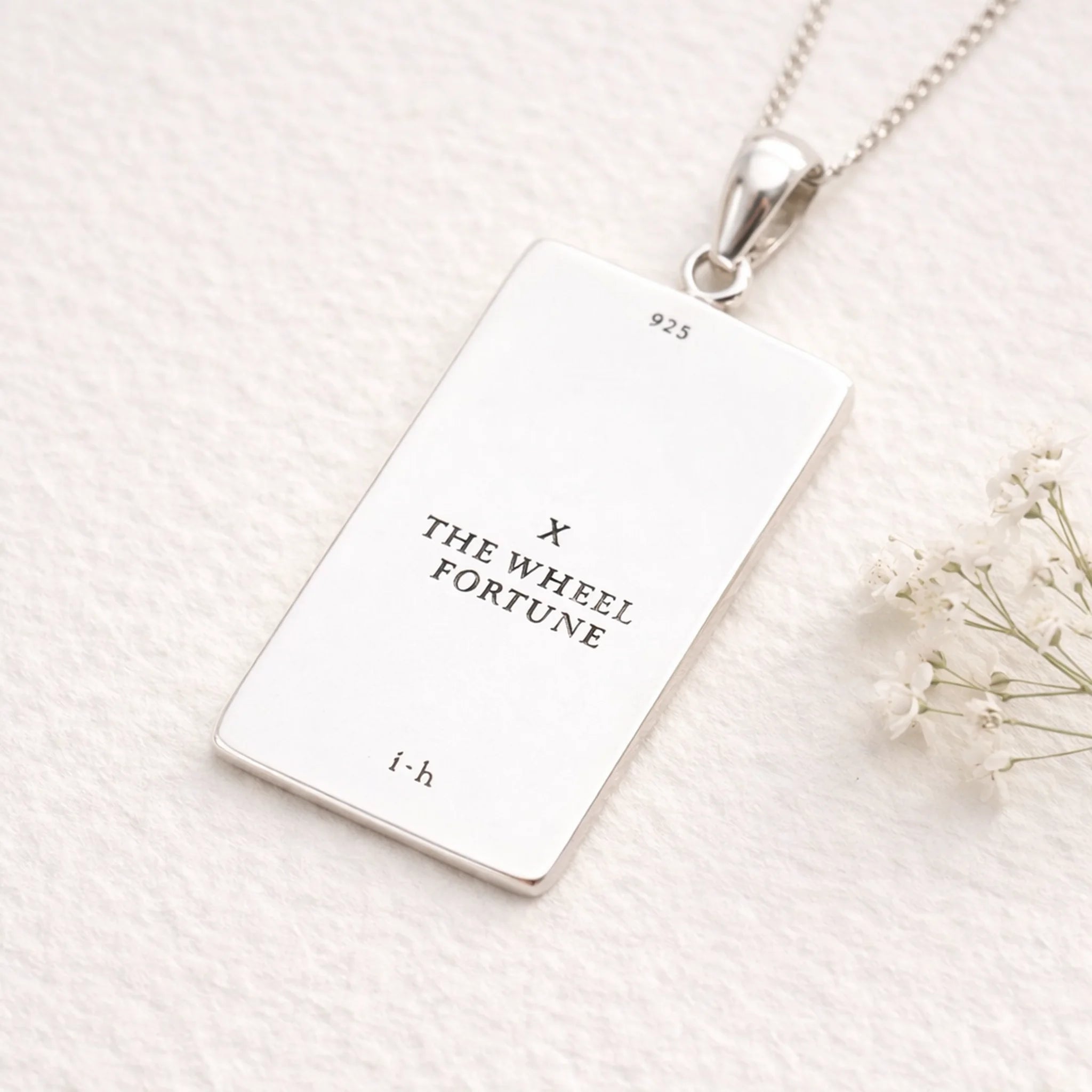 Silver necklace with a rectangular pendant on a white background