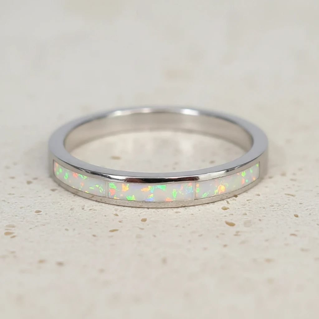 Silver ring with opal inlay on a light wooden surface
