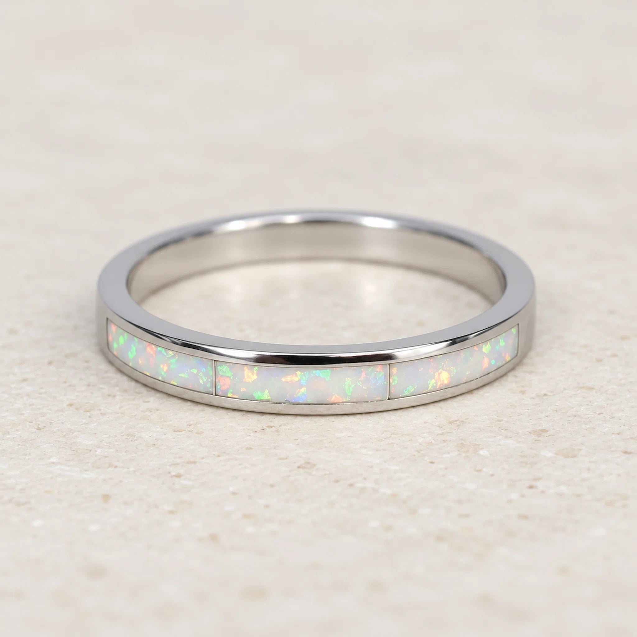 Silver ring with opal inlay on a light wooden surface