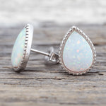 Teardrop-shaped opal earrings on a wooden surface