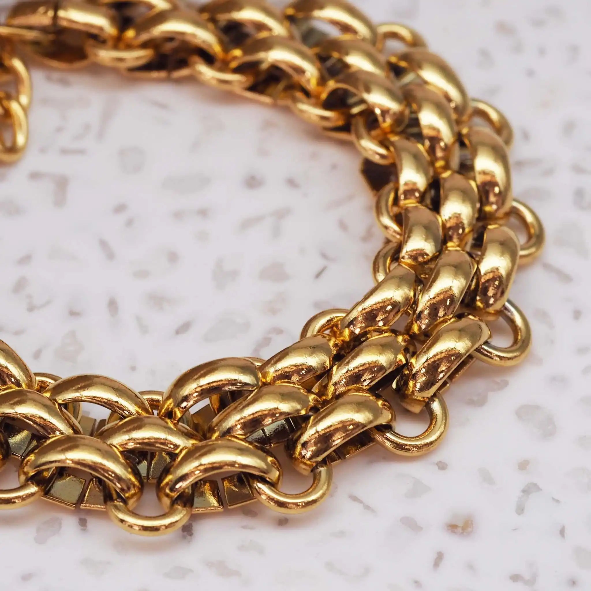 Close-up of polished gold chunky chain bracelet showing reflective waterproof titanium links. indie and harper.