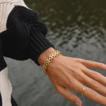 Woman wearing a chunky gold chain bracelet, waterproof titanium jewellery styled outdoors. indie and harper 