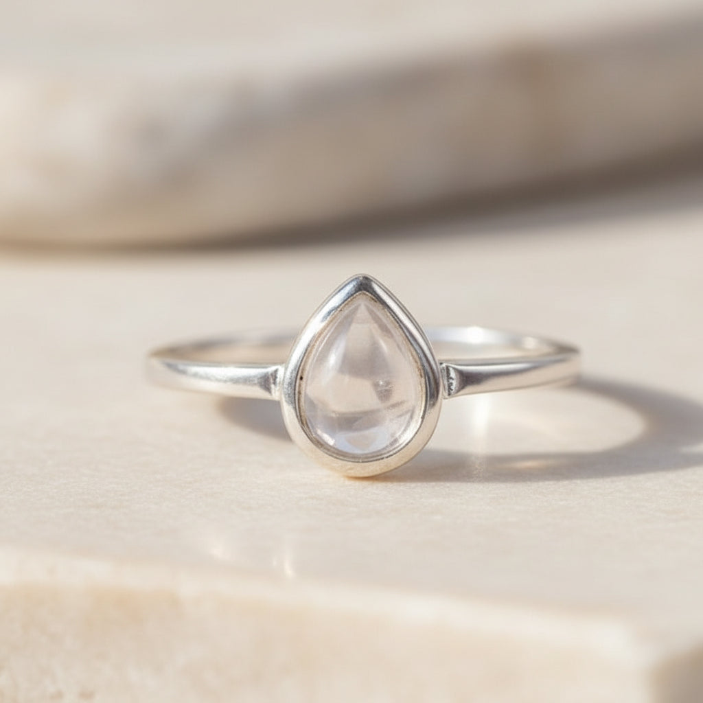 sterling Silver ring with a teardrop-shaped clear herkimer quartz gemstone on a beige background