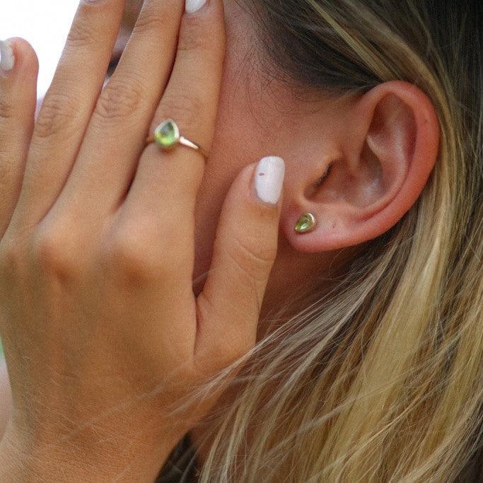 woman wearing august birthstone peridot earrings and ring by indie and harper