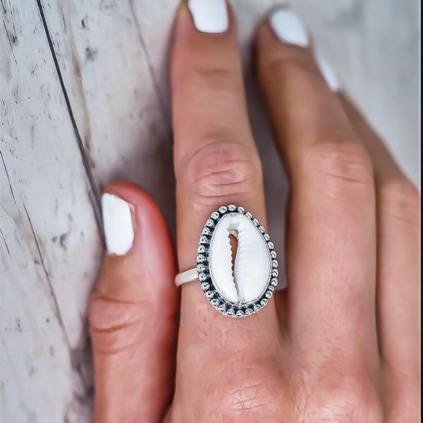 Hand wearing Cowrie Sea Shell Ring with rustic wood in background - womens sterling silver jewellery Australia