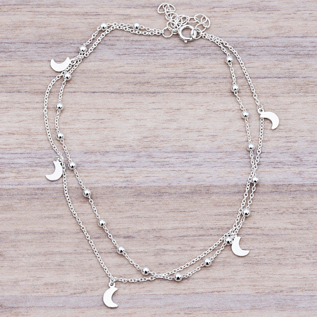 Sterling silver crescent moon anklet on a wooden surface