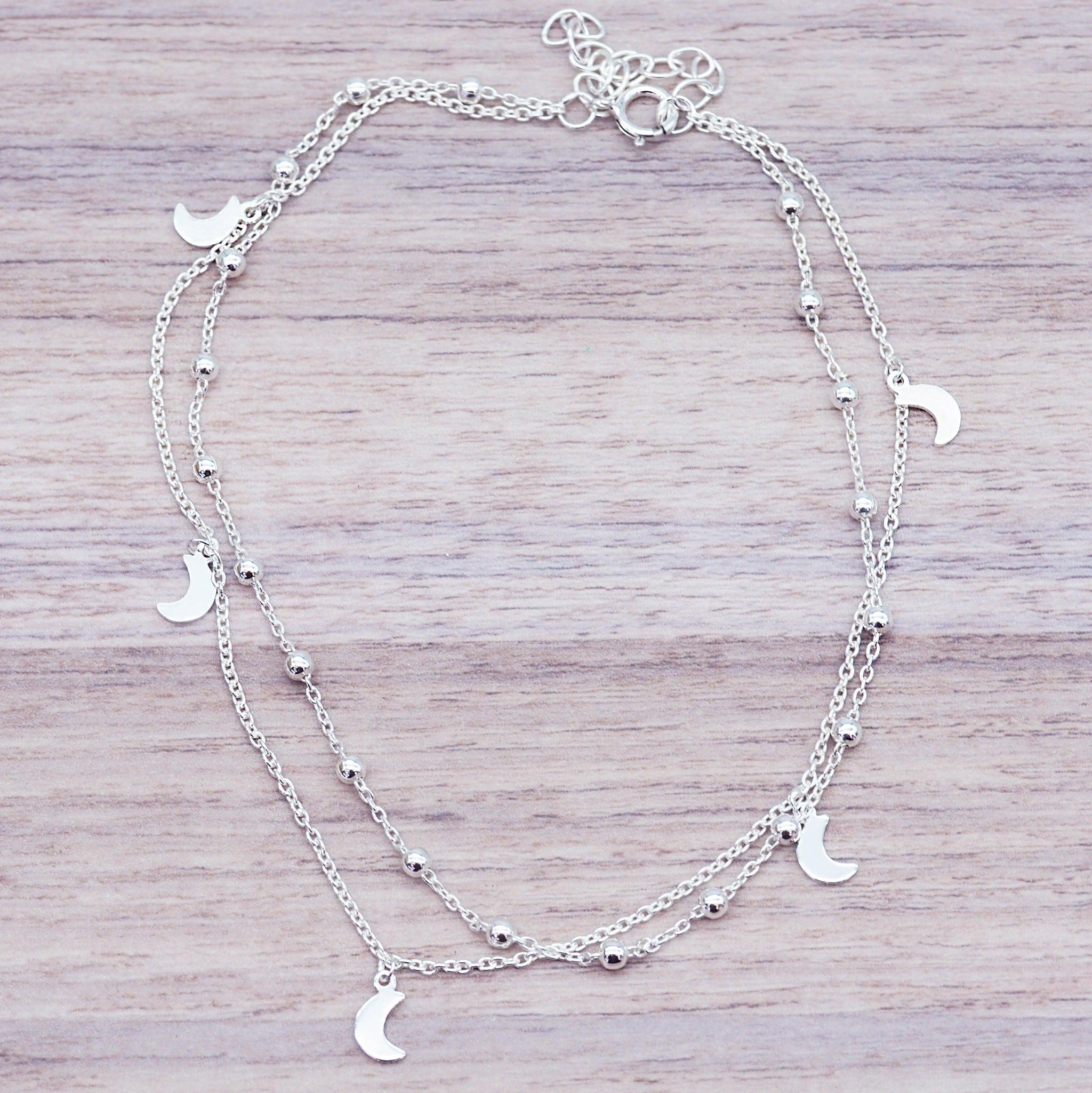 Sterling Silver double layered anklet with moon pendants on a wooden surface
