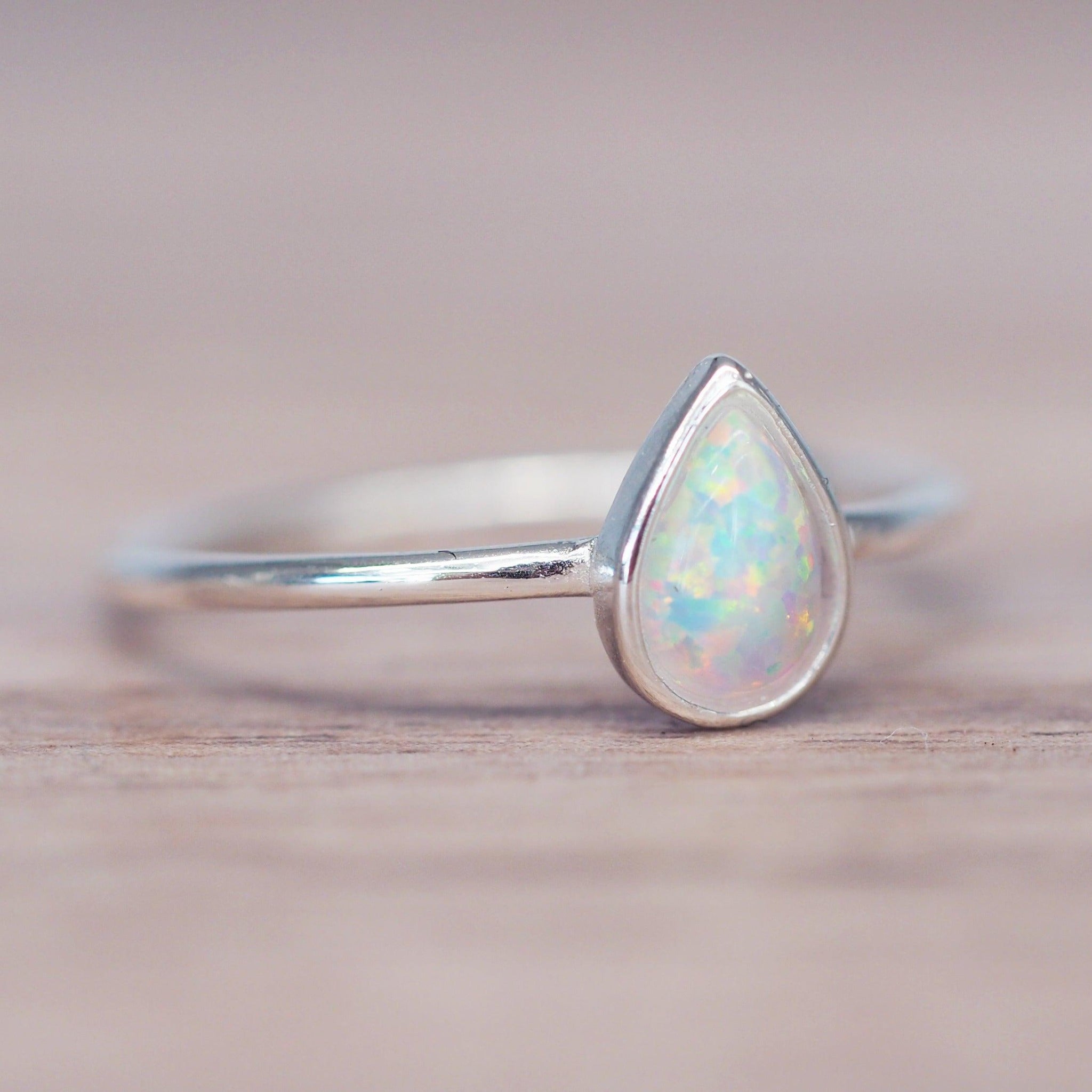 sterling silver dainty white Opal Ring on a wooden surface