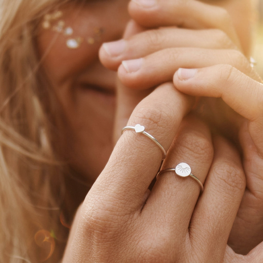 Hand wearing dainty sterling silver rings including the heart ring