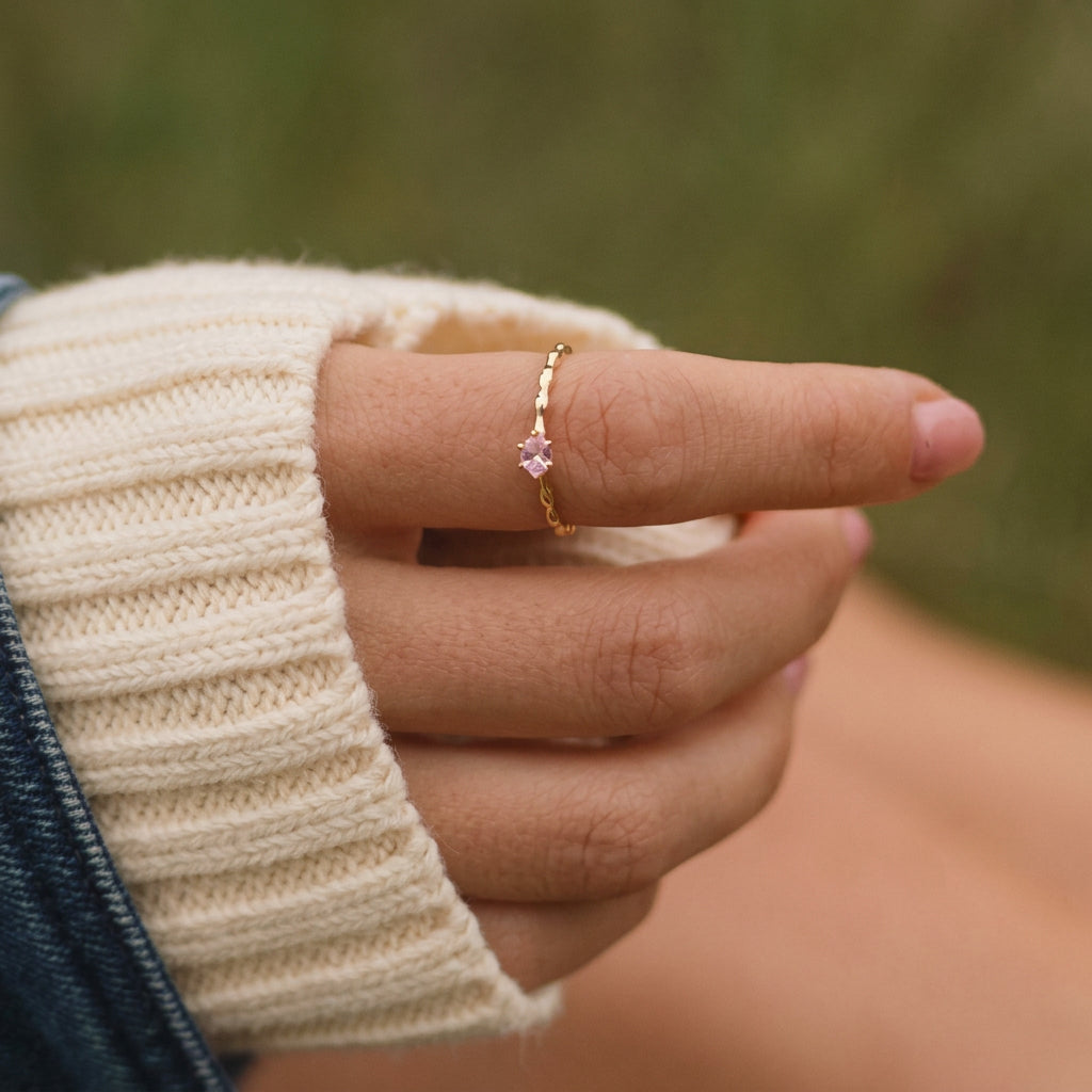Gold rose quartz ring worn on the hand against greenery