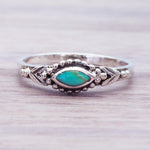 Silver ring with a turquoise stone on a light wooden surface