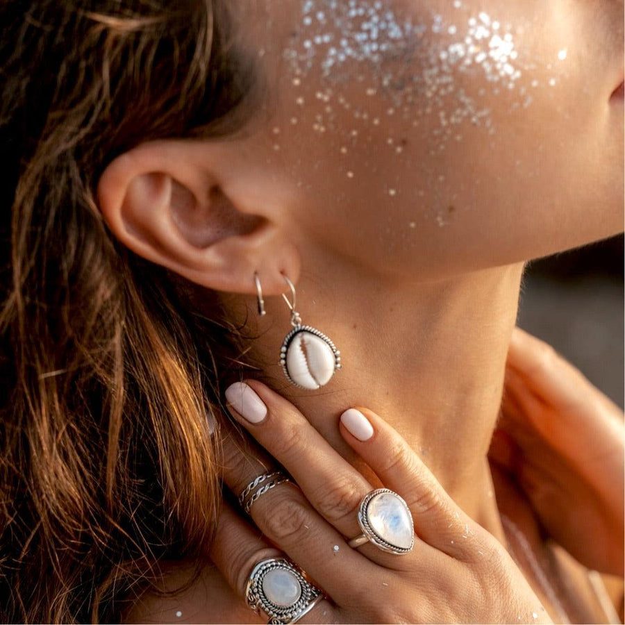 Woman with sparkles on her face wearing sterling silver Cowrie sea Shell Earrings - womens boho jewellery Australia 