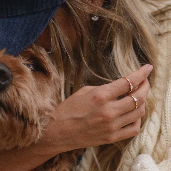 Woman hugging her dog and wearing Dainty Gold Rings with white topaz crystal - womens gold jewellery by indie and harper