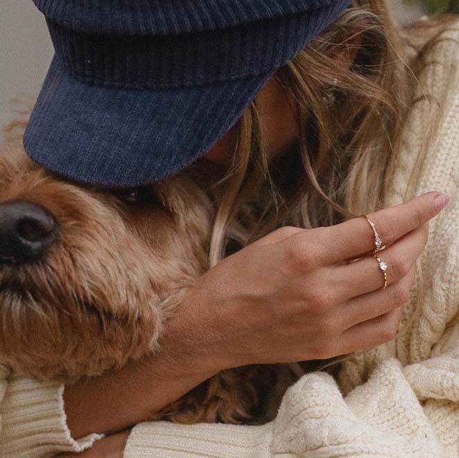 Woman hugging her cute dog and wearing Dainty Gold Rings with white topaz crystal - womens gold jewellery by indie and harper