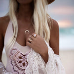 Woman on a beach wearing a white lace top with jewelry