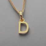 gold initial d necklace on grey background