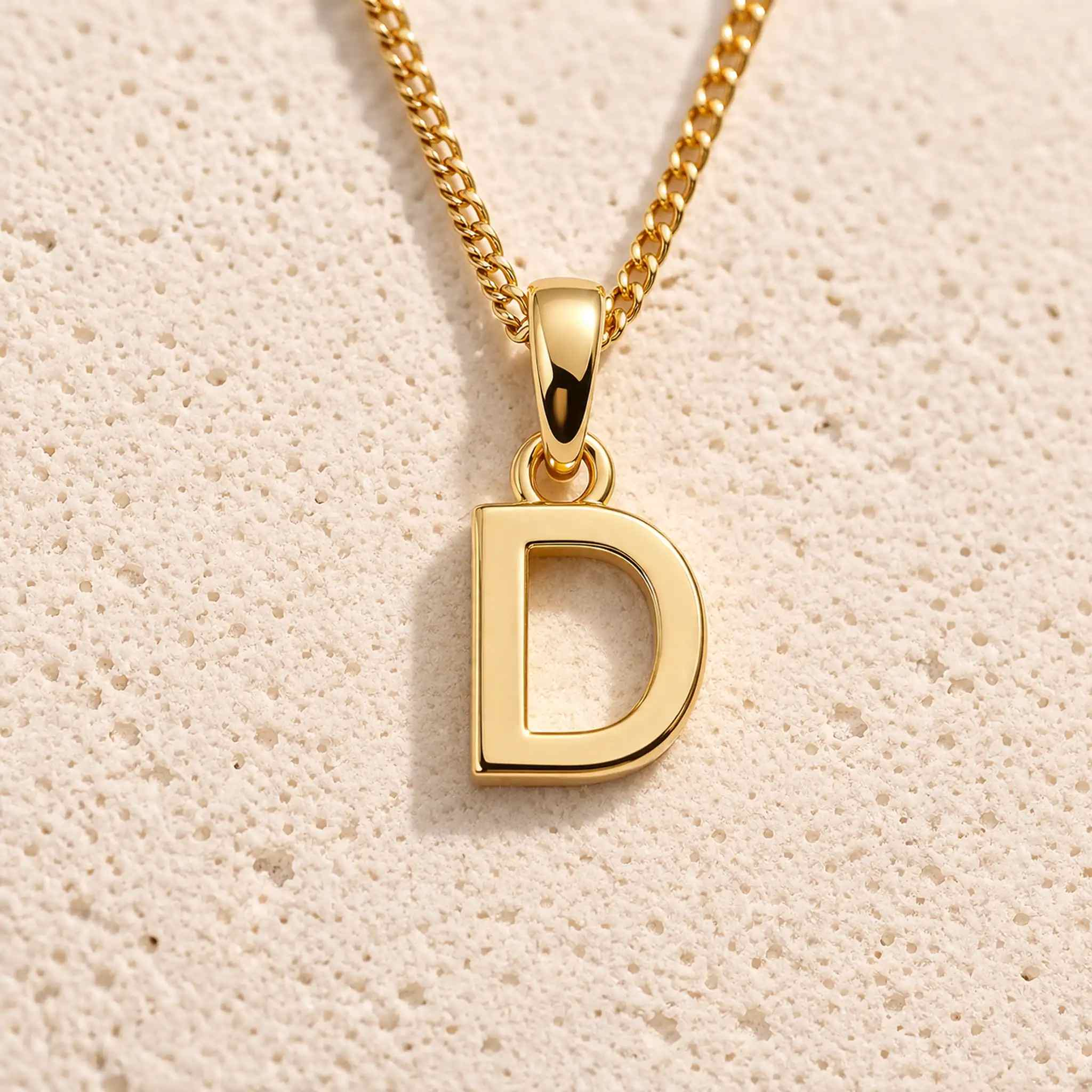gold initial d necklace on grey background