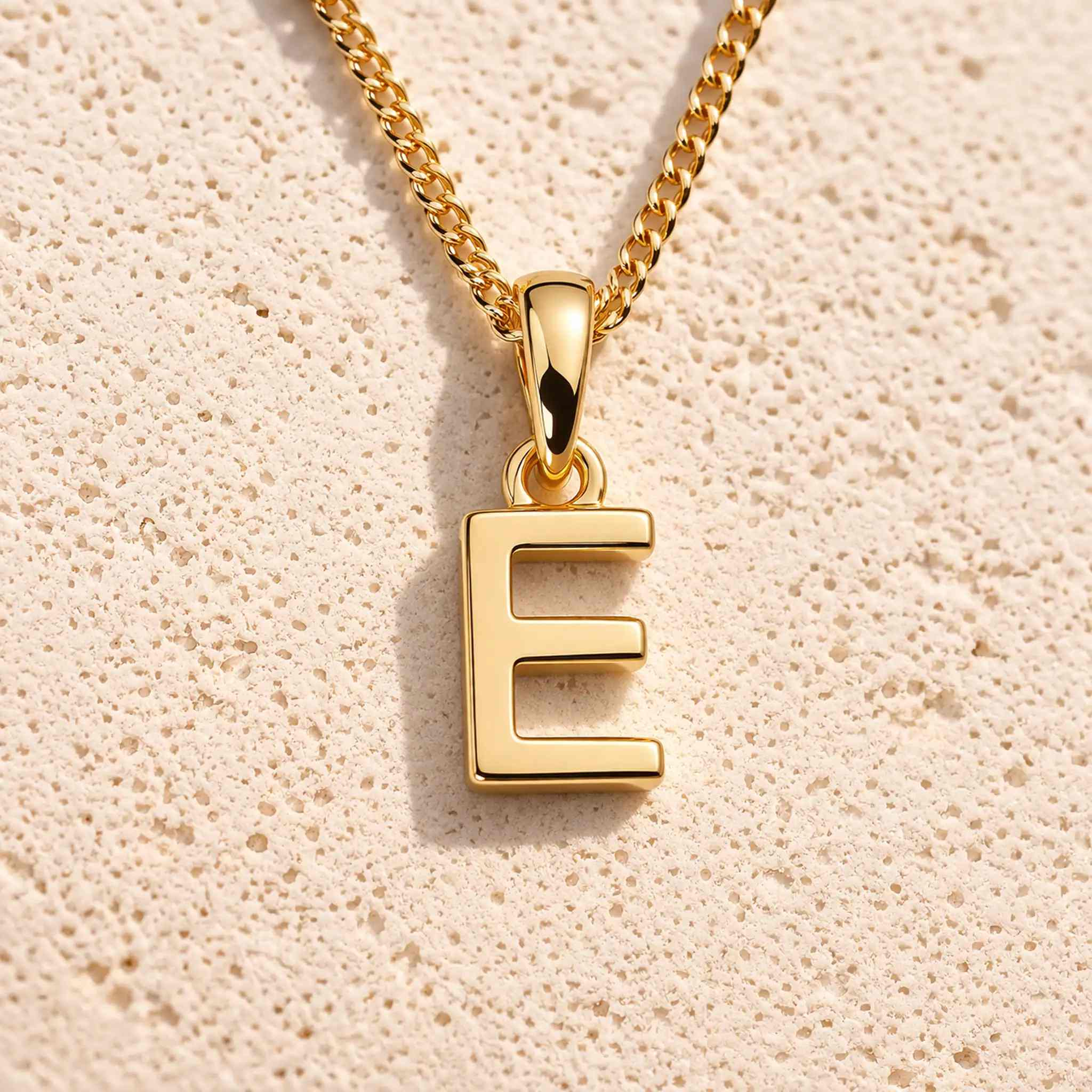 gold initial e necklace on grey background
