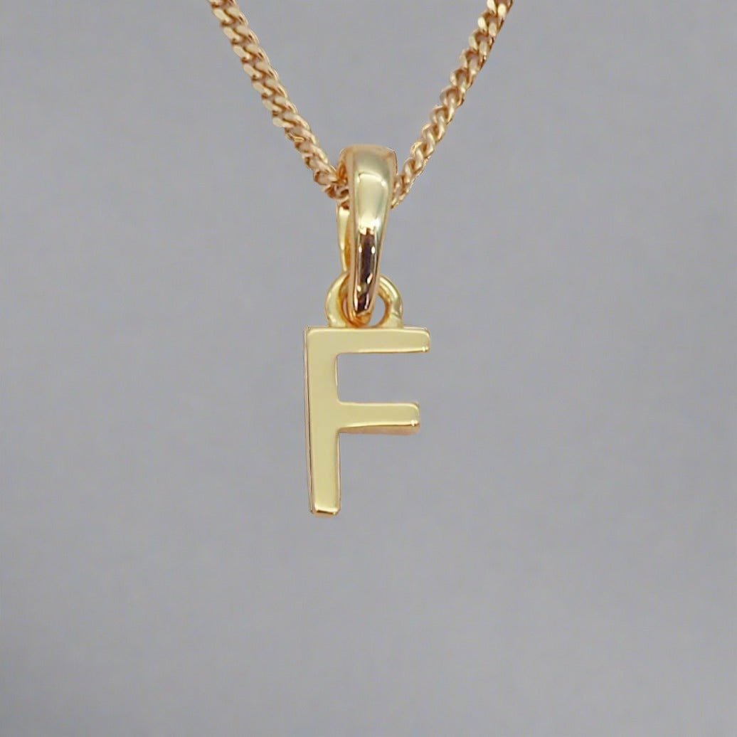 gold initial f necklace on a grey background