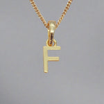 gold initial f necklace on a grey background