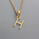 gold initial h necklace on a grey background