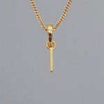 Gold necklace with a simple I initial pendant on a gray background