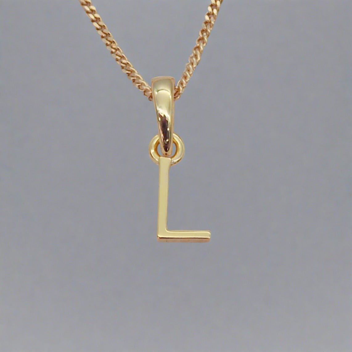Gold necklace with a 'L' pendant on a gray background